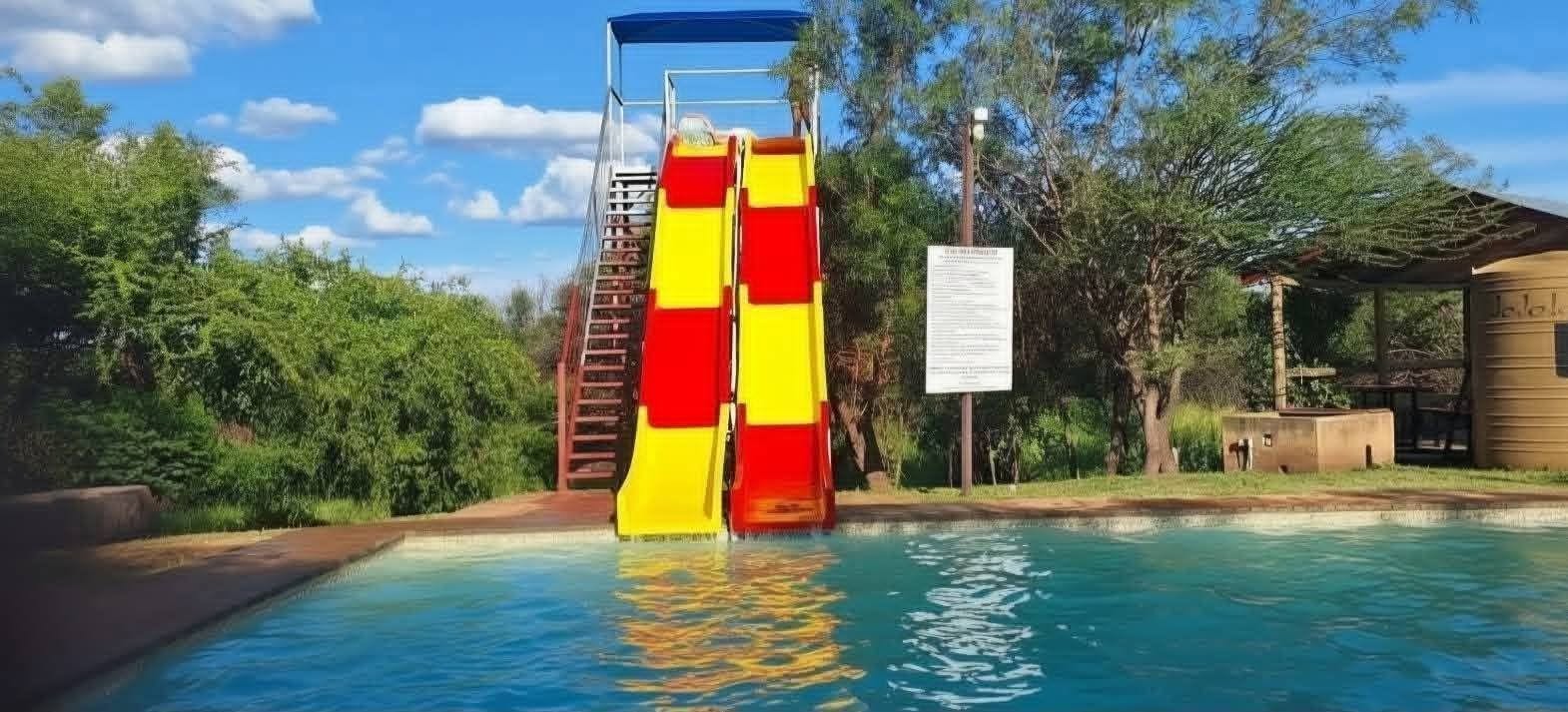 Red and yellow dual water slides dropping into a blue pool