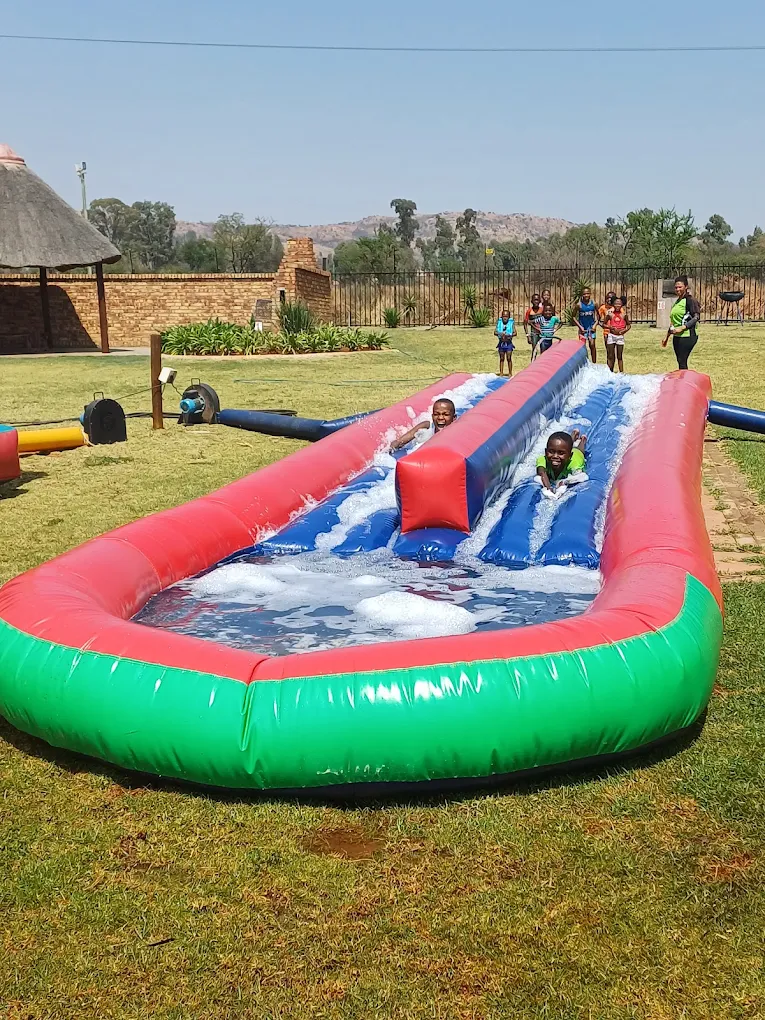 Kids sliding on a red-and-blue inflatable water slide on the lawn