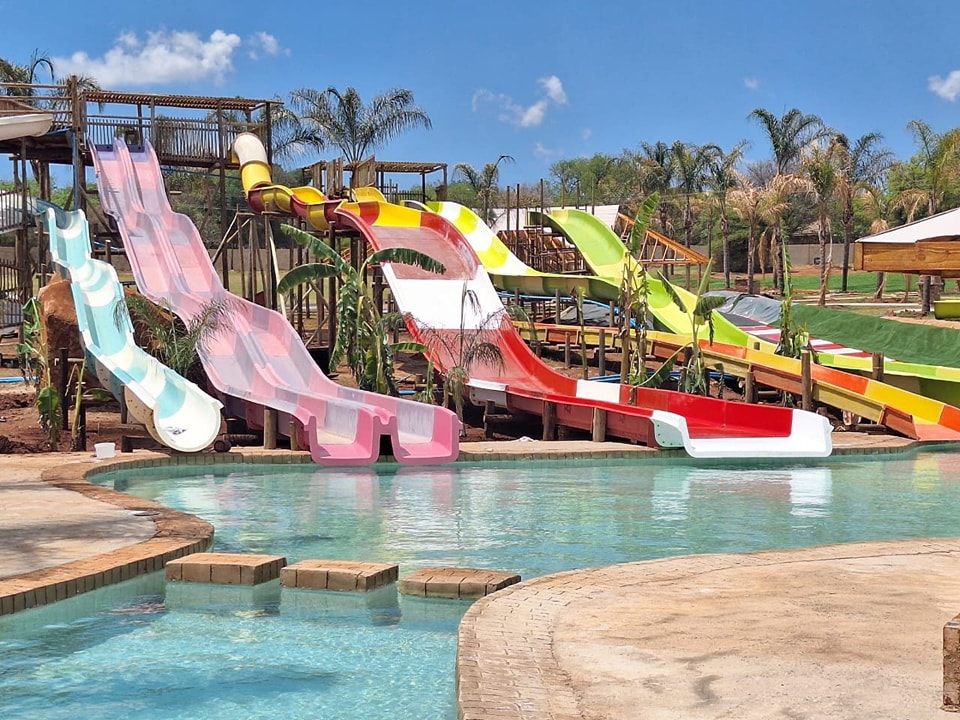 Pink, red and green water slides dropping into a brick-edged pool