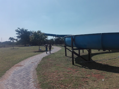 Blue water slide beside a brick path and a covered walkway on open grass