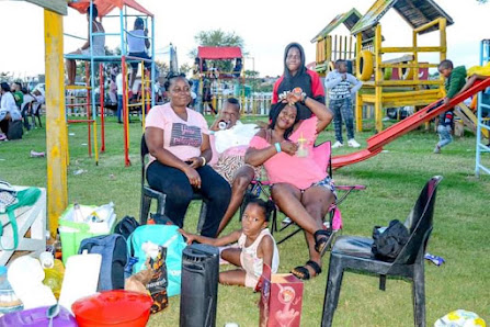 Family sitting on camp chairs in front of a colourful kids' playground